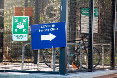 Motosiklet parkının yanındaki sokakta COVID-19 test kliniği tabelası. Coronavirus Delta salgını