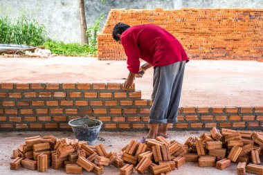 İnşaat işçisi dış duvarlar için çimentoya tuğla yerleştiriyor..