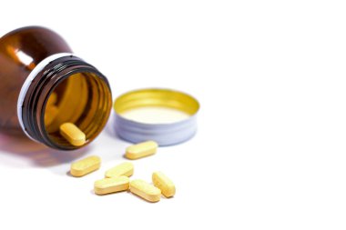 İlaç şişesi beyaz arka plana ilaç ya da vitamin döküyor..