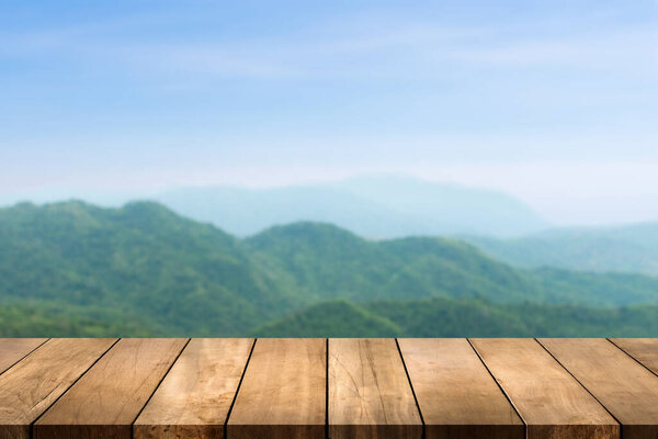 Wooden table top with nature mountain and forest blurred background. Copy space for your display or montage product design.