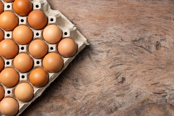 Chicken eggs in carton box on wooden table background.