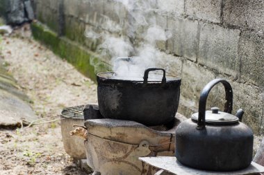 Eski tencereye kirli ve kaynamış su buhar kömür sobası ile kase.