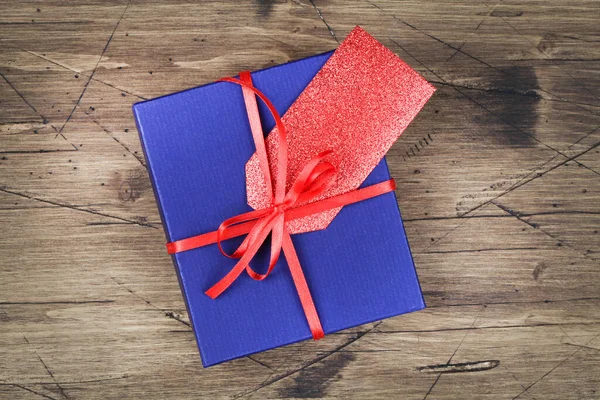 Caja de regalo azul con cinta roja y etiqueta de regalo en blanco sobre fondo de madera — Foto de Stock