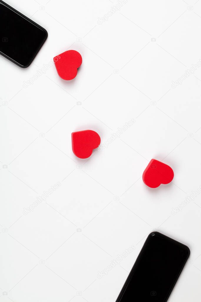 Red hearts and two mobile phones on white background. Internet dating, copy space, Valentines day concept.