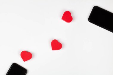 Kırmızı kalpler ve beyaz arka planda iki cep telefonu. İnternet randevusu, fotokopi alanı, Sevgililer Günü konsepti.