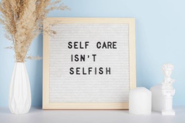 Dried pampas grass in vases, candles and felt letter board with phrase self care is not selfish on blue background. concept of mental health