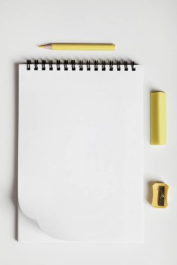 Ofis masası, not defterli çalışma alanı, sarı kalem, silme ve kalem açacağı, ofis malzemeleri konsepti. Düz konum, üst görünüm, kopyalama alanı.