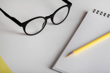 Ofis masası, çalışma odası, defter, sarı kalem ve gözlük. Minimum konsept. Düz konum, üst görünüm, kopyalama alanı.