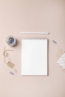 Ofis masası çalışma alanı, defter, kalem, ataçlar boş kağıt etiketli ve eğreltiotu dallı cam kavanoz. 