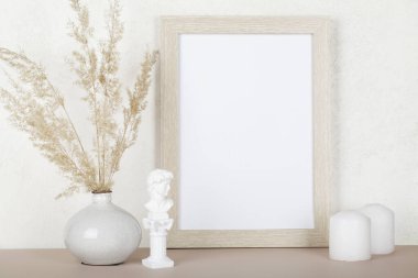 Portre boş ahşap çerçeve modeli, kurutulmuş otlar, küçük heykel ve beyaz arka planda mumlar, iç dekorasyon, ev tasarımı. Sanat konsepti. Boşluğu kopyala. 