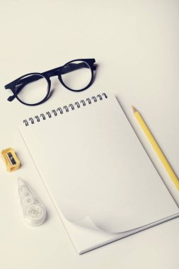 Ofis masası, çalışma odası, defter, sarı kalem, silme, kalem açacağı ve gözlük. Minimum konsept. Düz konum, üst görünüm, kopyalama alanı.