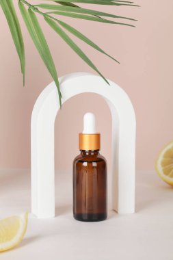 Koyu kehribar cam şişe, kemer, limon ve bej arka planda palmiye yaprağı. kopyalama alanı. Güzellik konsepti, minimalizm marka ambalajı..