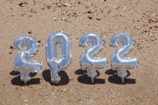 Navidad y feliz año nuevo concepto. globos de plata en forma de números 2022 en el fondo de arena. — Foto de Stock
