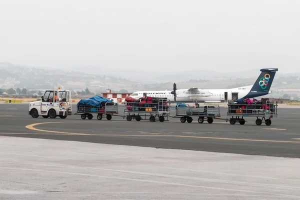 Bagage kar op de landingsbaan van het vliegveld van Macedonië een regenachtige dag — Stockfoto