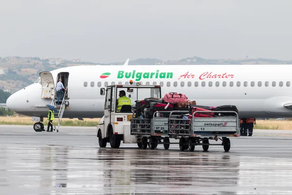 Bagage kar op de landingsbaan van het vliegveld van Macedonië een regenachtige dag — Stockfoto
