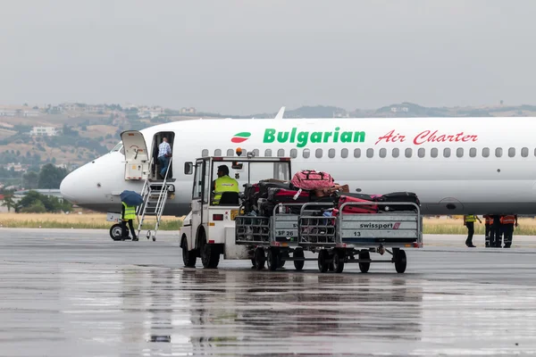 Gepäckwagen auf der Landebahn des Flughafens Mazedonien an einem regnerischen Tag — Stockfoto