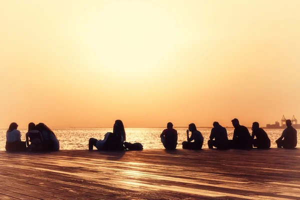 People relax on the waterfront at sunset — Stock Photo, Image