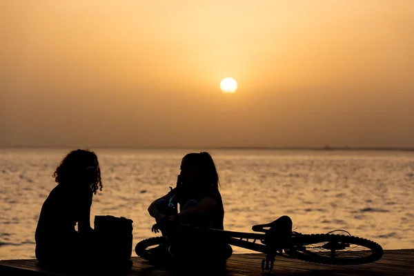 Mensen ontspannen aan de waterkant bij zonsondergang — Stockfoto