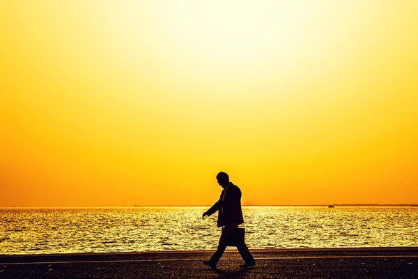 Silhuetas de pessoas desfrutando de um passeio à beira-mar da cidade — Fotografia de Stock