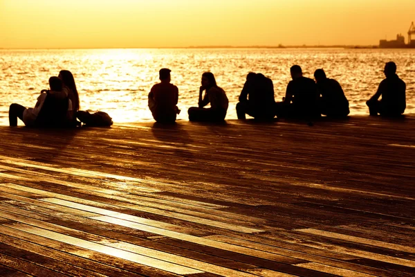 People relax on the waterfront at sunset — Stock Photo, Image