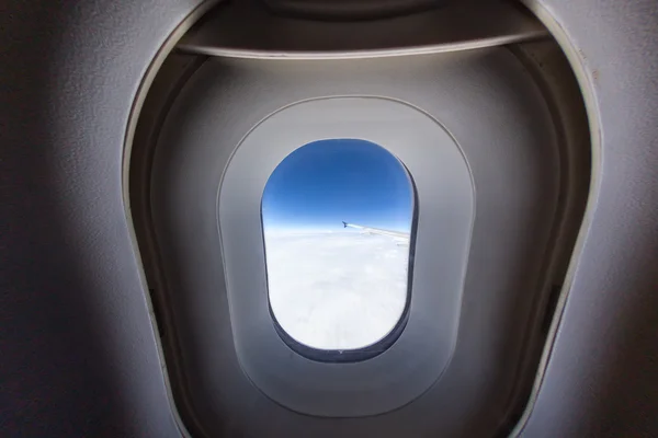 Janela de avião com asa e céu nublado atrás . — Fotografia de Stock