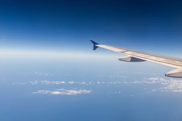 Wing af flyvemaskine flyver over skyerne i himlen - Stock-foto