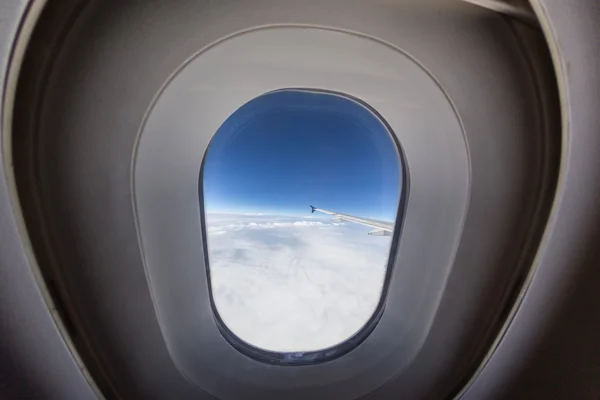 Vliegtuig venster met vleugel en bewolkte hemel achter. — Stockfoto