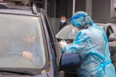 Selanik, Yunanistan - 10 Aralık 2020. Coronavirus 'a karşı korumak için özel bir takım elbise giyen bir tıp çalışanı, covid-19 için hızlı bir test uygular.