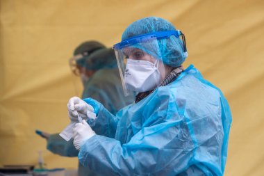 Selanik, Yunanistan - 10 Aralık 2020. Coronavirus 'a karşı korumak için özel bir takım elbise giyen bir tıp çalışanı, covid-19 için hızlı bir test uygular.