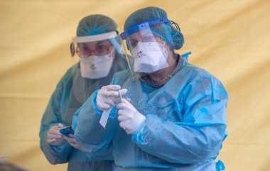 Selanik, Yunanistan - 10 Aralık 2020. Coronavirus 'a karşı korumak için özel bir takım elbise giyen bir tıp çalışanı, covid-19 için hızlı bir test uygular.