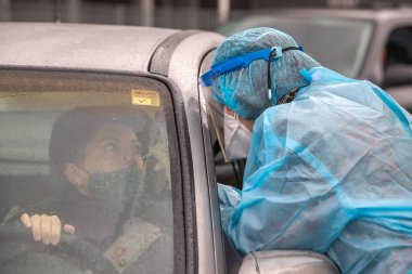 Selanik, Yunanistan - 10 Aralık 2020. Coronavirus 'a karşı korumak için özel bir takım elbise giyen bir tıp çalışanı, covid-19 için hızlı bir test uygular.