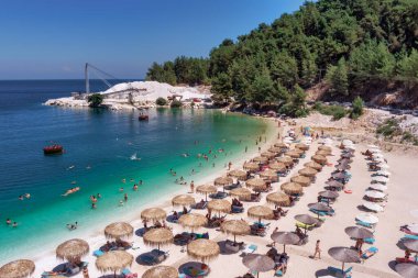 Porto Vathy, Mermer Sahili, Thassos, Yunanistan - 19 Temmuz 2021: Porto Vathy plajının zümrüt ve şeffaf Akdeniz manzaralı plajı, plaj şemsiyeleri ve yüzen turistlerle dolu
