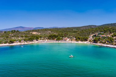 Yukarıdan bakıldığında, zümrüt ve şeffaf bir Akdeniz manzarası, plaj şemsiyeleri ve dinlenip yüzen turistlerle dolu beyaz bir plaj. Psili Ammos, Thassos Adası, Yunanistan.