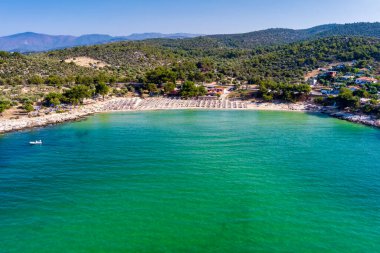 Yukarıdan bakıldığında, zümrüt ve şeffaf bir Akdeniz manzarası, plaj şemsiyeleri ve dinlenip yüzen turistlerle dolu beyaz bir plaj. Psili Ammos, Thassos Adası, Yunanistan.
