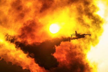 5 Ağustos 2021 'de Yunanistan' ın Mora kentinde Antik Olympia yakınlarında gündoğumunda çıkan yangını söndürmeye çalışan bir itfaiye uçağı su yükünü boşaltıyor.
