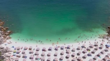 Mermer plaj, Thassos adası, Yunanistan - 19 Temmuz 2021: Yukarıdan bakıldığında, plaj şemsiyeleri ve yüzen ve dinlenen turistlerle dolu beyaz plajlı bir zümrüt ve saydam Akdeniz manzarası.