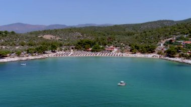 Yukarıdan bakıldığında, zümrüt ve şeffaf bir Akdeniz manzarası, plaj şemsiyeleri ve dinlenip yüzen turistlerle dolu beyaz bir plaj. Psili Ammos, Thassos Adası, Yunanistan - 17 Temmuz 2021