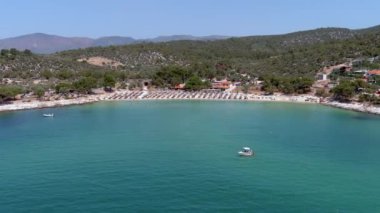 Yukarıdan bakıldığında, zümrüt ve şeffaf bir Akdeniz manzarası, plaj şemsiyeleri ve dinlenip yüzen turistlerle dolu beyaz bir plaj. Psili Ammos, Thassos Adası, Yunanistan - 17 Temmuz 2021