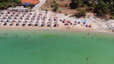Psili Ammos, Thassos Adası, Yunanistan - 17 Temmuz 2021: Yukarıdan bakıldığında, plaj şemsiyeleriyle dolu beyaz bir plaj ve dinlenip yüzen turistlerle dolu bir zümrüt ve şeffaf Akdeniz manzarası. 