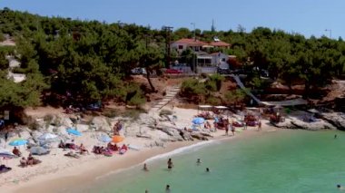 Psili Ammos, Thassos Adası, Yunanistan - 17 Temmuz 2021: Yukarıdan bakıldığında, plaj şemsiyeleriyle dolu beyaz bir plaj ve dinlenip yüzen turistlerle dolu bir zümrüt ve şeffaf Akdeniz manzarası. 