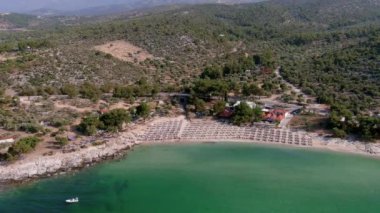 Yukarıdan bakıldığında, zümrüt ve şeffaf bir Akdeniz manzarası, plaj şemsiyeleri ve dinlenip yüzen turistlerle dolu beyaz bir plaj. Psili Ammos, Thassos Adası, Yunanistan - 17 Temmuz 2021