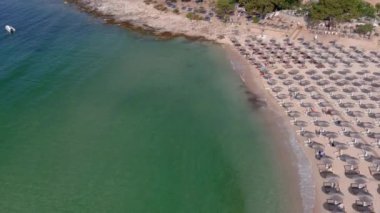 Yukarıdan bakıldığında, zümrüt ve şeffaf bir Akdeniz manzarası, plaj şemsiyeleri ve dinlenip yüzen turistlerle dolu beyaz bir plaj. Psili Ammos, Thassos Adası, Yunanistan - 17 Temmuz 2021