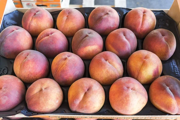 Vers geoogste perziken gestapeld in een krat — Stockfoto