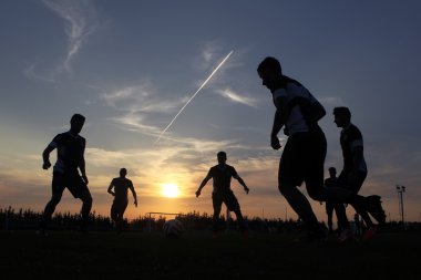 Silhouettes of footballers on the sunset sky clipart