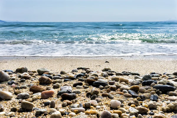 Волна моря на песчаном пляже с морскими камнями спереди — стоковое фото