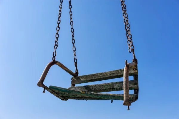 Old rusty swing against blue sky — Stock Photo, Image