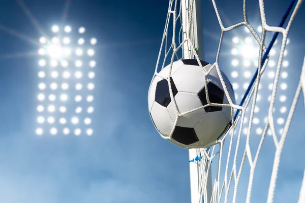 Balón de fútbol en la red de portería con luces de estadio en el fondo —  Fotos de Stock