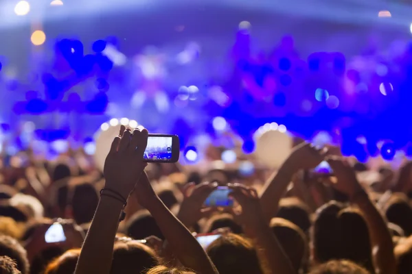 Pessoas tirando fotos com telefone inteligente de toque durante uma música — Fotografia de Stock