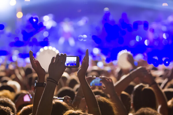 People taking photographs with touch smart phone during a music 