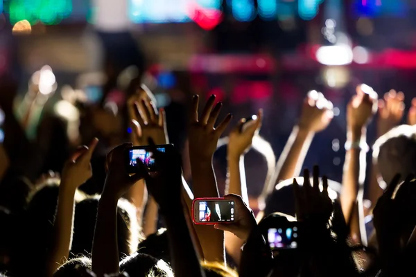 Personas que toman fotografías con un teléfono inteligente táctil durante una música — Foto de Stock